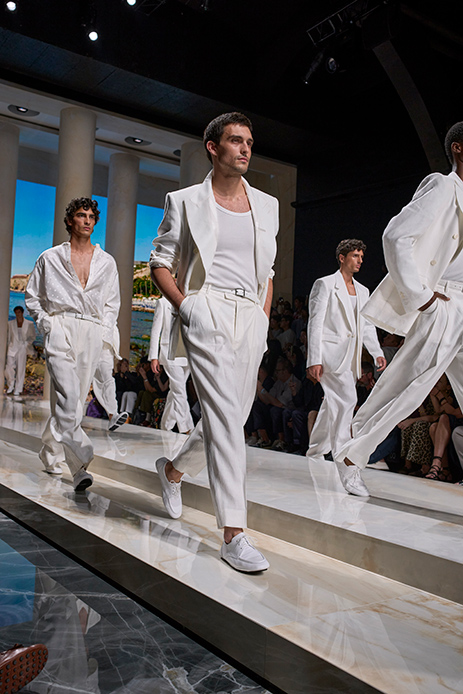 Modello in completo bianco con giacca monopetto, pantaloni con pinces e cintura, sneaker bianche, sfilata Dolce&Gabbana Uomo SS27