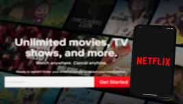 Logo Netflix su smartphone davanti alla schermata della piattaforma streaming, simbolo delle difficoltà del titolo a Wall Street.
